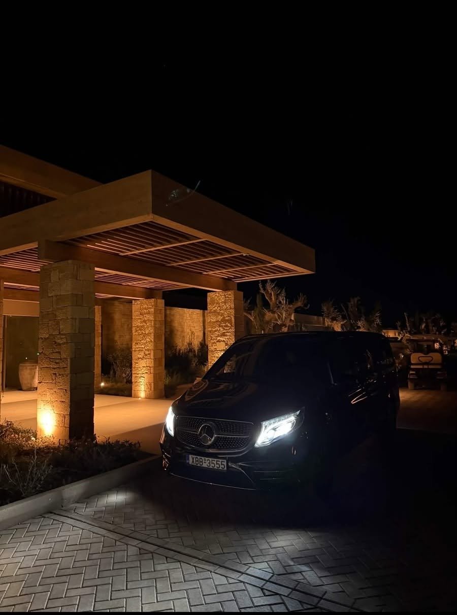 Chania airport transfer in a black Mercedes V-Class arriving at a hotel entrance at night